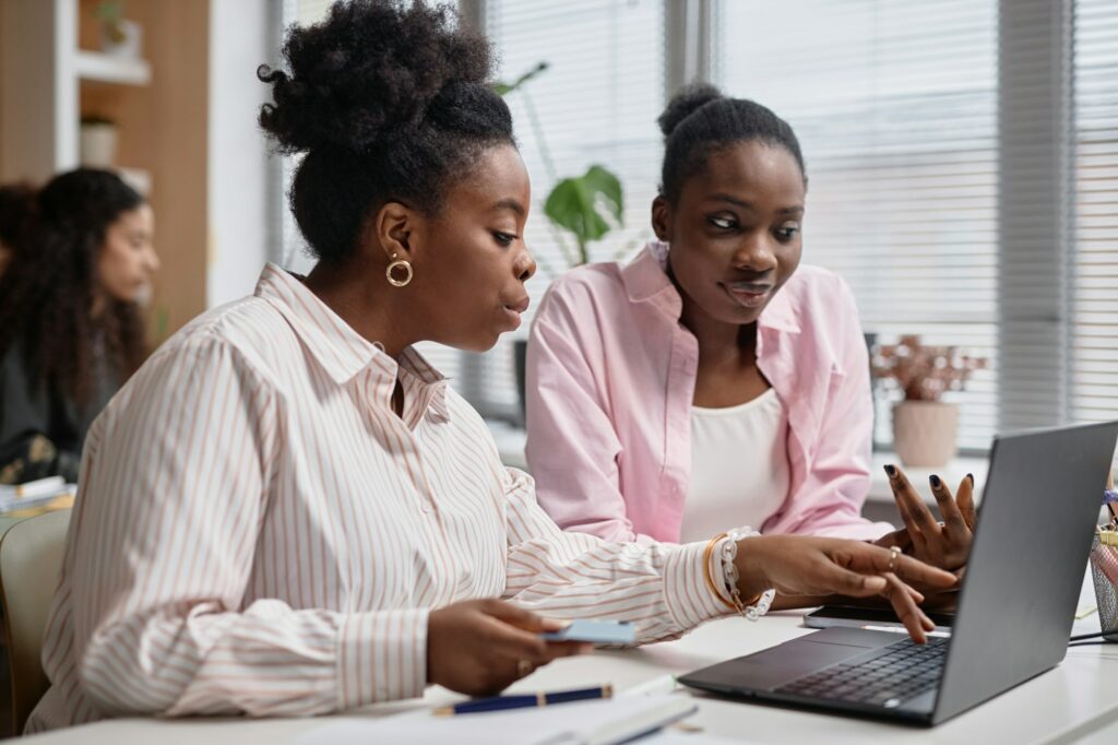 Two Black Business Women Talk Shop Using Computer